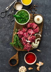Raw meat and vegetables on a dark background top view. Cooking  beef meat