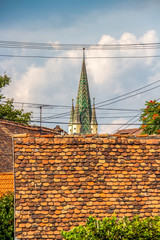 St. Margaret's Lutheran Church bell tower behind blurred house roofs at Medias, Sibiu County,...