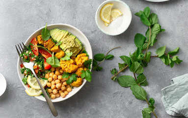 Buddha bowl Vegetarian healthy balanced food Aloo gobi, chickpeas, tomato, avocado, tabule salad spinach