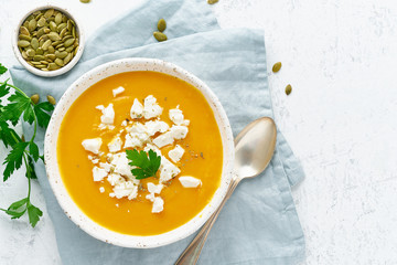 Pumpkin cream soup with feta cheese, autumn homemade food, white background, top view, copy space