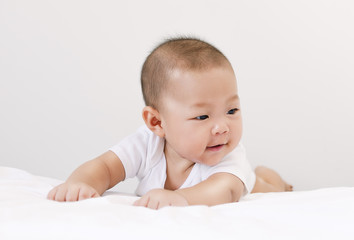 little small asian happy baby infant relaxing and smiling in bed