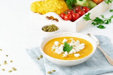 Pumpkin cream soup with feta cheese, autumn homemade food, white background, closeup, copy space