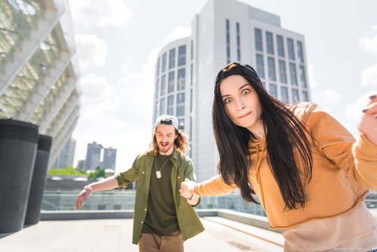 selective focus of brunette woman with staring eyes looking at camera, holding hands with man, standing on roof