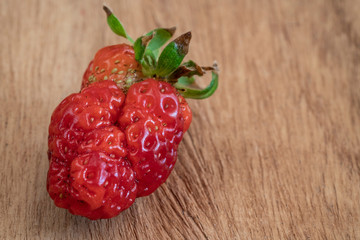 unusual shaped strawberry on a wooden table