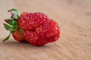 unusual shaped strawberry on a wooden table