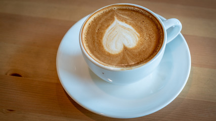 Drinking hot cappuccino coffee cup with heart shape latte art