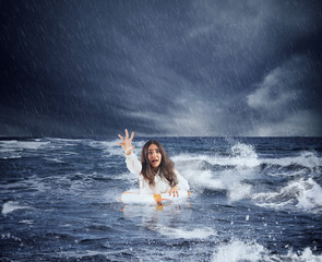 Businesswoman in the ocean with lifebelt asks help during a storm