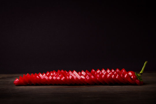 Pimiento rojo troceado o picado  sobre tabla r&uacute;stica con fondo oscuro