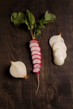 R&aacute;bano con cebollas picadas sobre tabla de madera oscura, comida vegetariana