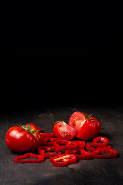 tomates con pimiento rojo troceado sobre mesa de madera r&uacute;stica 