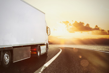 White truck moving on the road in a natural landscape at sunset