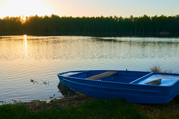 fishing boat in a calm lake water/old  fishing boat/ wooden fishing boat in a still lake water 