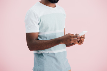 cropped view of african american man using smartphone, isolated on pink