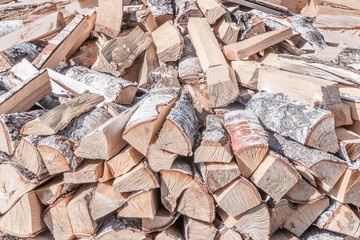 abstract background of tightly stacked in the woodpile chopped birch firewood close up