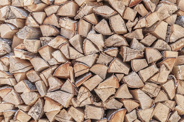 abstract background of tightly stacked in the woodpile chopped birch firewood close up