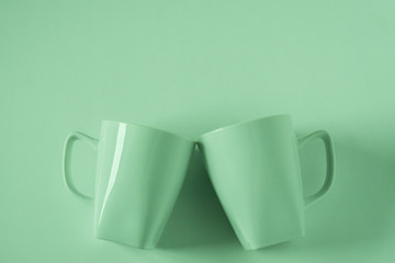 Green coffee mugs on green background clinking in cheers with empty copyspace - Powered by Adobe