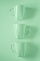 3 green coffee mugs on green background in a vertical row with empty copyspace