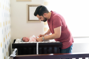 New father changing diaper of his newborn baby