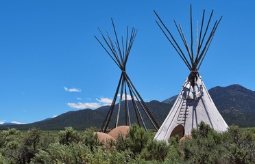 two tepees, one without skin, showing the poles © Darla Hallmark