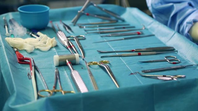 Concept medicine, surgery. Operating table with a tool for surgery, closeup, blue light. On the table are spread out the sterilny instruments of surgeons, scalpels, clips, tampons, syringes.