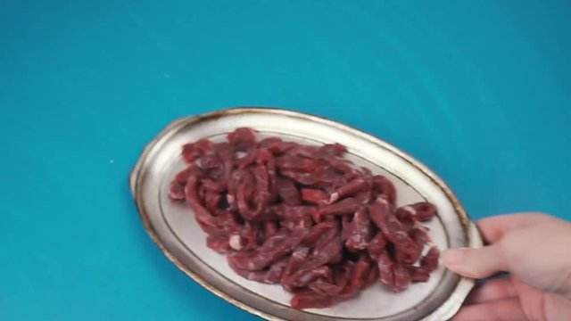 Preparing meat for dinner. Ingredients; raw meat, tomatoes, green peppers and onions on blue background