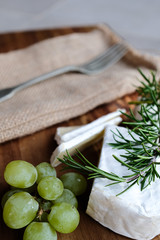 Käseplatte, Käse und Rosmarin mit Besteck auf einer Holzplatte