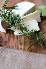 K&auml;seplatte, K&auml;se und Rosmarin mit Besteck auf einer Holzplatte