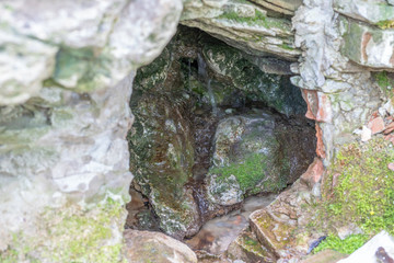 Holy Water Grotto Sources Background. Holy trickle of water flows out of cave.