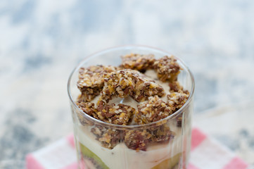 Granola, Greek yogurt, kiwi and banana in a glass beaker on gray background close-up view from the side. Fitness, figure, body and healthy food