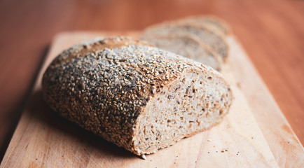 Sliced multigrain homemade bread on a wooden cutting board at home