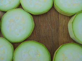 fresh green zucchini sliced lined on a wooden surface