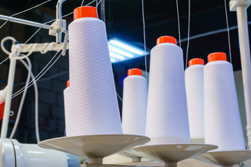bobbins with white threads secured in an industrial sewing machine