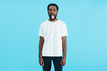 handsome african american man sticking tongue out isolated on blue © LIGHTFIELD STUDIOS