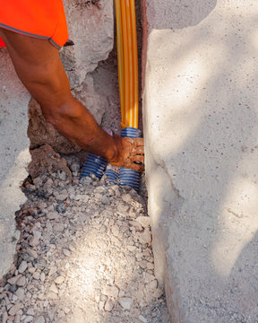 Worker inserts fiber optic cables buried in a micro trench