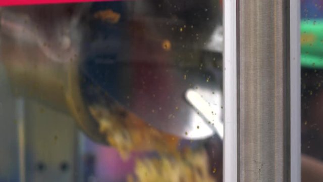 This close up video shows the hands of a carnival popcorn vendor flipping the kettle over and dumping the hot fresh popcorn for a customer.