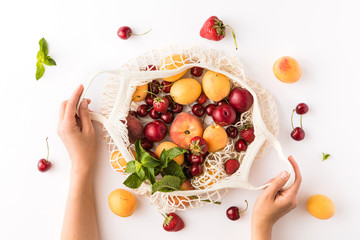 Top view of mesh shopping bag with organic eco fruits isolated on white background. Caring for the...