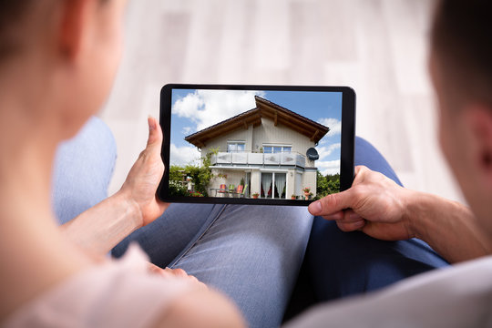 Couple Looking At House On Tablet