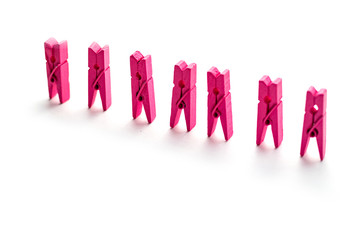 Pink wooden clothespins isolated on white background stand in a row