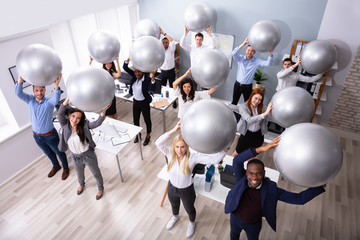 Businesspeople Stretching Using Fitness Ball In Office