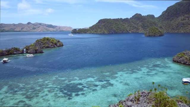 Aerial view of small rocky islands with  boats surrounded by turquoise sea. Palawan May 2017. Flyover.