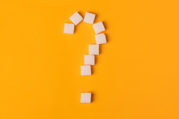 white sugar cubes shaped as a question mark on orange background. Top view. Diet unhealty sweet addiction concept