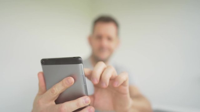 Defocussed man types and swipes on prop smartphone. Copy space
