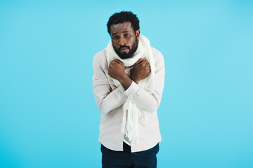 sick african american man in warm scarf, isolated on blue