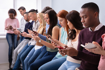 Row Of Young People Using Cellphones