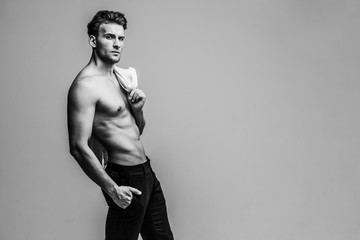 Portrait of a shirtless young and handsome model holding his white shirt. Studio shot. Copy space.