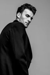 Portrait of young and handsome model with a strong look in a classic black style clothing. Studio shot. Copy space. © alesgon
