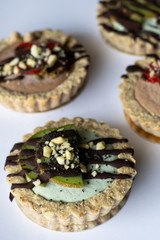 Raw vegan tartlets on the white plate. Healthy desserts, close up
