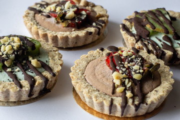 Raw vegan tartlets on the white plate. Healthy desserts, close up