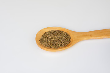 Una cuchara de madera con granos de cominos