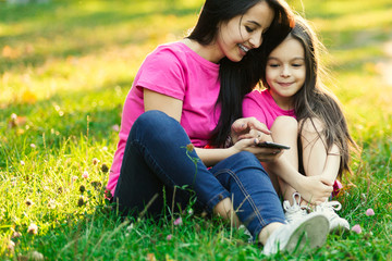 Fototapeta premium Young mother with pretty daughter make photo in park